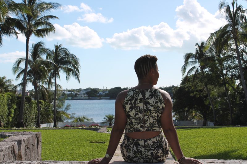 This Bahamian Gyal blogger, Rogan Smith sits on steps with her back turned to the camera at the French Cloisters on Paradise Island in The Bahamas