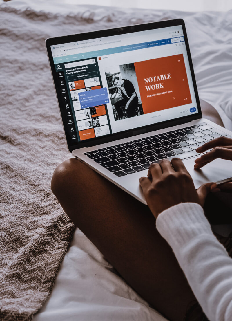 Photo of a black girl sitting on the bed designing a poster in Canva. Photo by Cotton Bro for Pexels