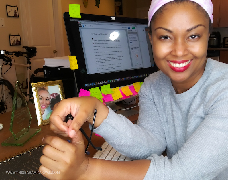 This Bahamian Gyal blogger, Rogan Smith sits in her Washington, DC home blogging on her computer. She is smiling at the camera. 