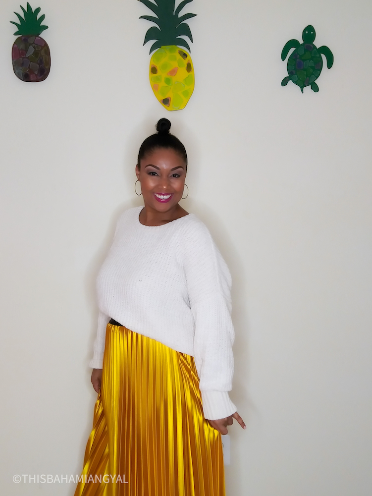 Beauty and lifestyle blogger, Rogan Smith wears a mustard-yellow satin midi skirt with a cream-coloured sweater. 