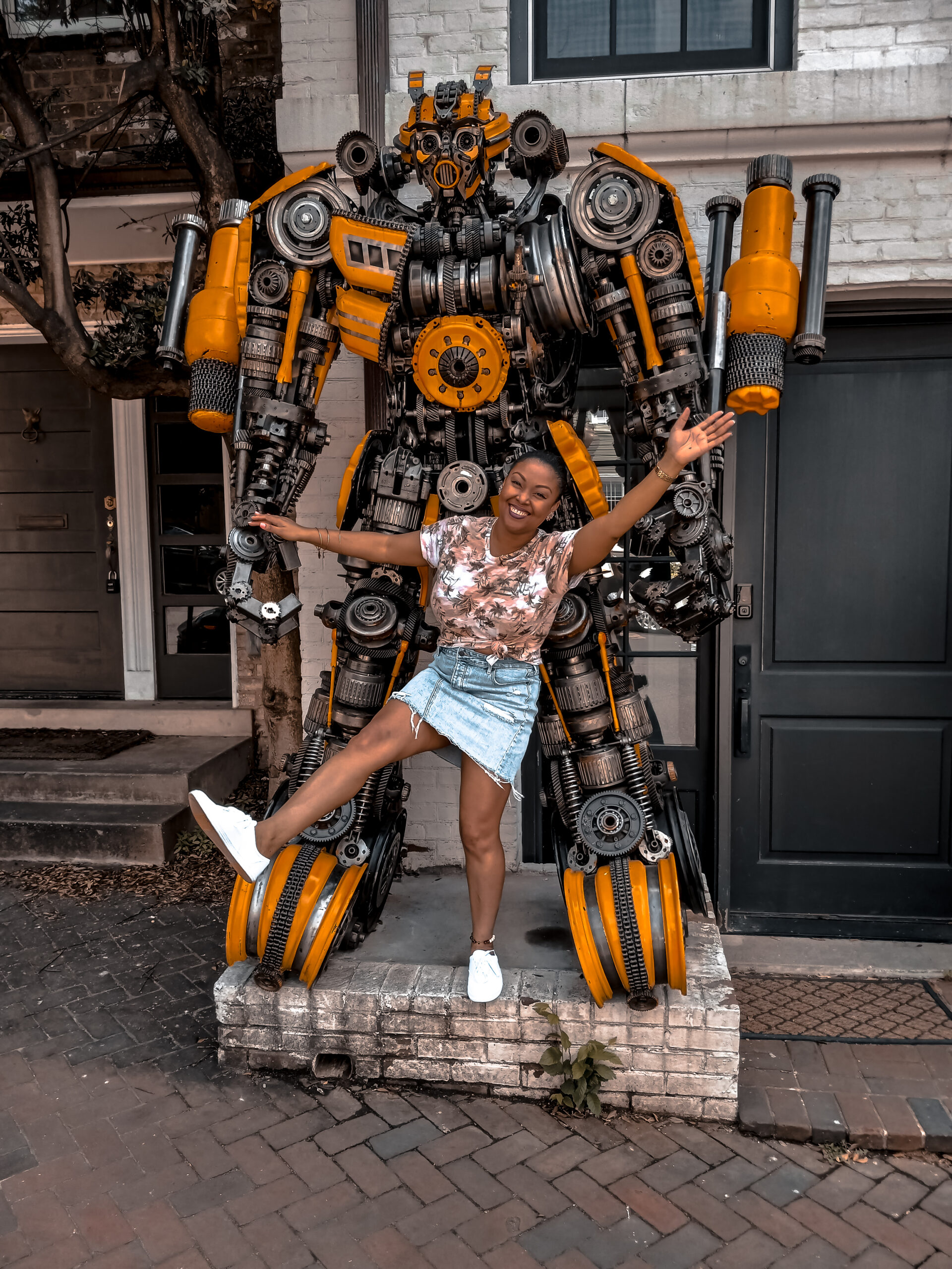 DC blogger Rogan Smith of This Bahamian Gyal poses in front of the Transformers house in Georgetown DC. She is shown in the picture with the robot, Bumblebee.