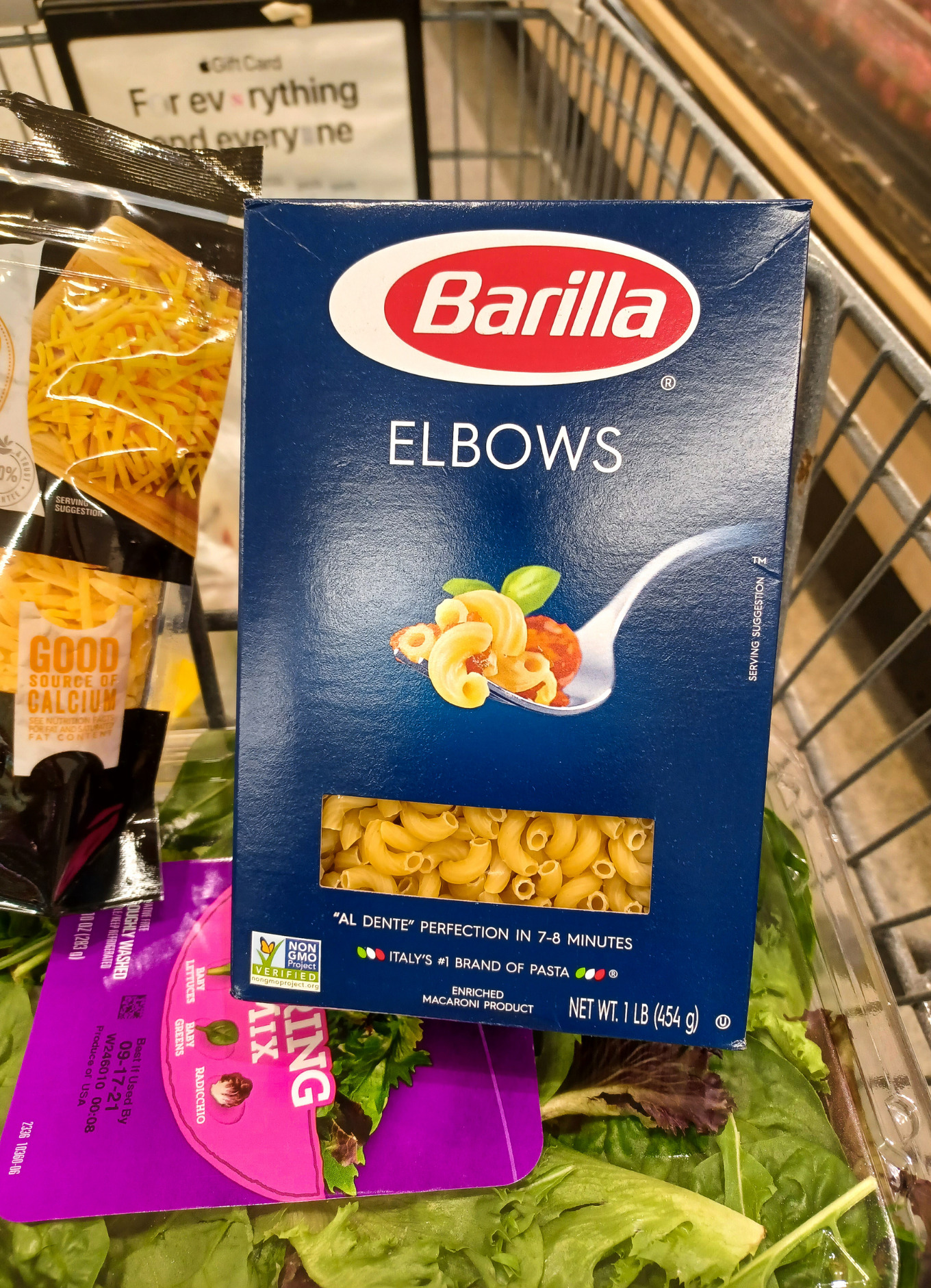 A box of Barilla elbow macaroni in a grocery cart