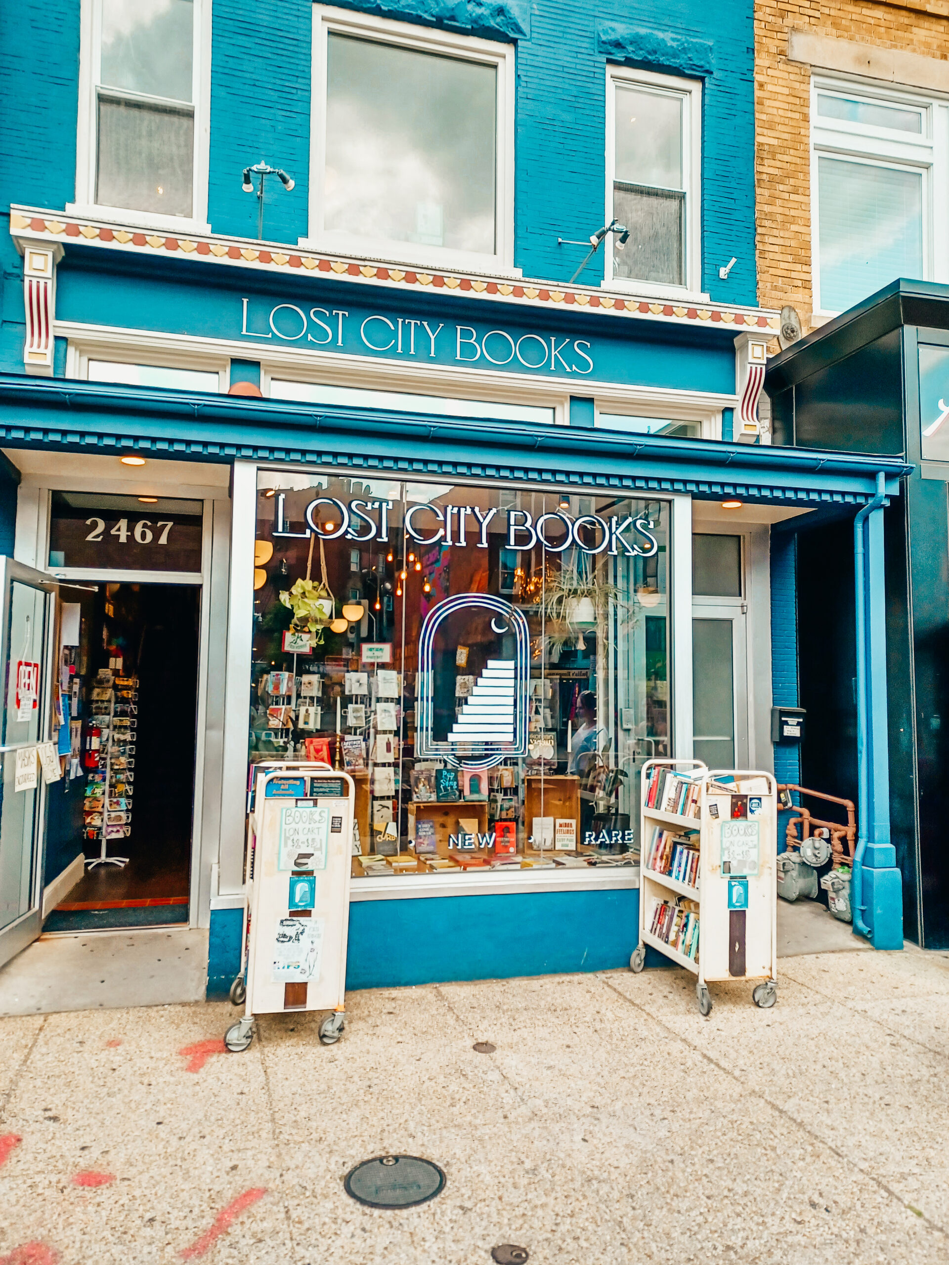 Exterior of Lost City Books bookstore in Adams Morgan. The building is blue and white with shelves of books on the outside.