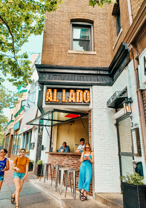 A white woman plays with her cell phone in front of Al Lado in Adams Morgan, Washington, DC.