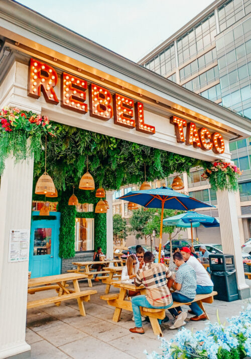 Rebel Taco on U Street in Washington, DC is one of the best taco restaurants in the city. People sit outside eating their food as the Rebel Taco marquee looms above their heads.