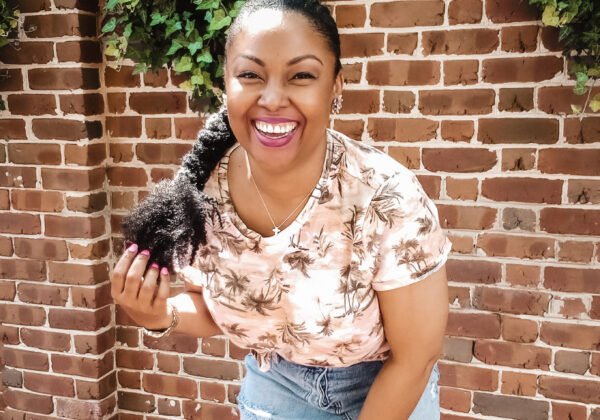 Washington DC-based blogger, Rogan Smith smiles and poses in front of a brick wall in Georgetown, DC