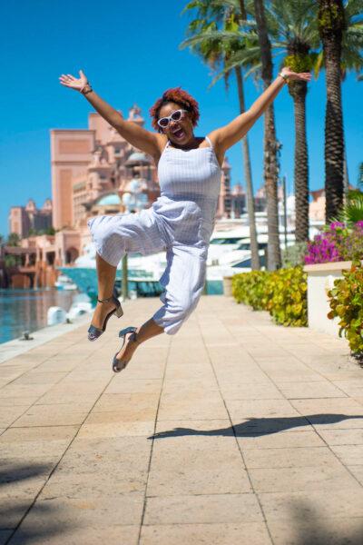 This Bahamian Gyal blogger and Creative Director, Rogan Smith jumps for joy in Marina Village at the Atlantis Paradise Island resort in The Bahamas. The Bahamas will open for travel on July 1.