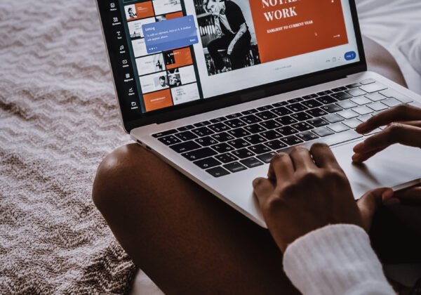Photo of a black girl sitting on the bed designing a poster in Canva. Photo by Cotton Bro for Pexels