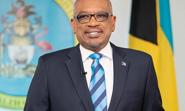 Photo of Bahamas Prime Minister Dr Hubert Minnis as he delivers an address to the nation. A gold, blue and black Bahamian flag is shown in the background. 