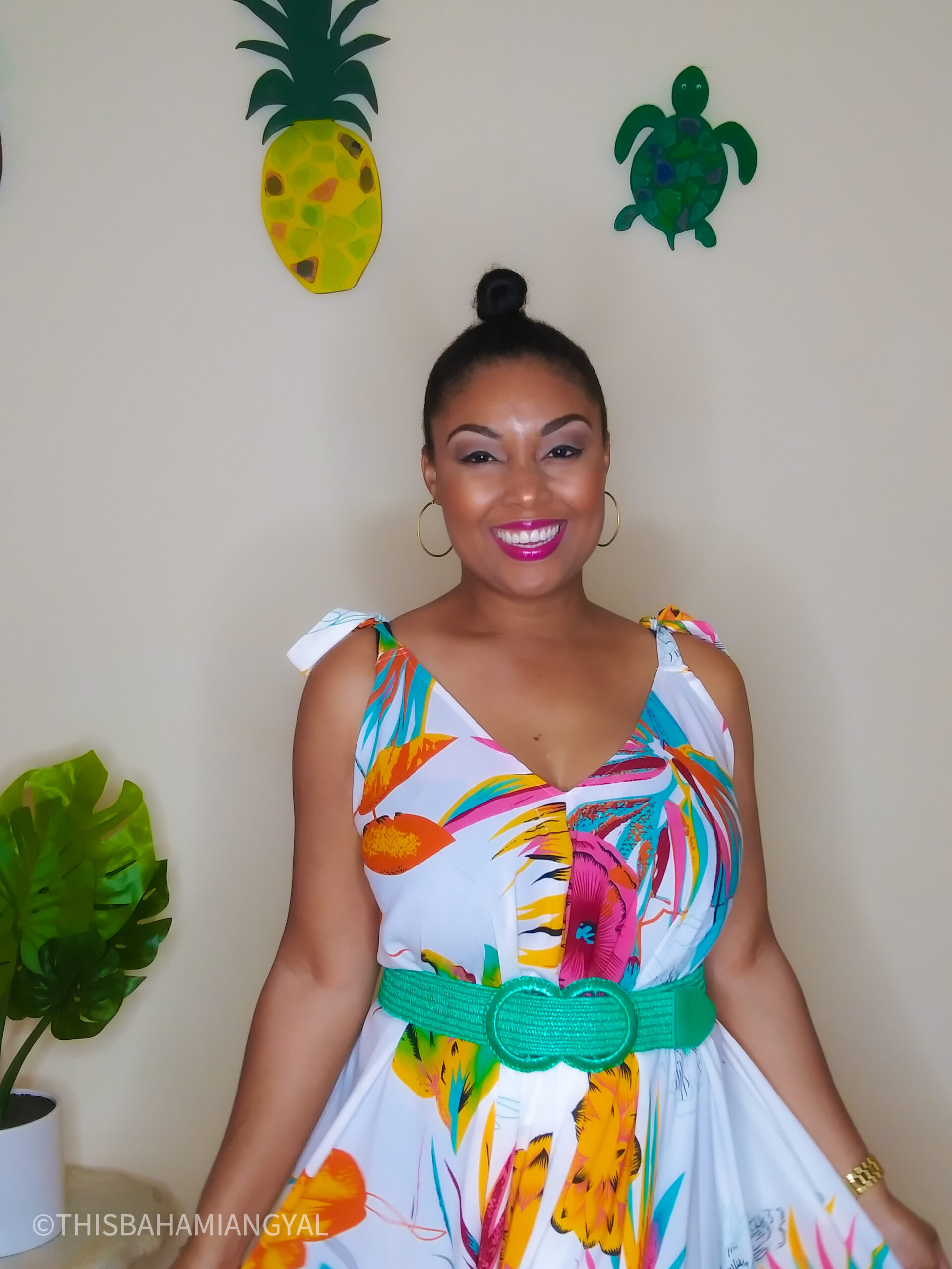 This Bahamian Gyal lifestyle and beauty blogger, Rogan Smith poses for the camera. She's wearing a colourful tropical romper with a green belt.