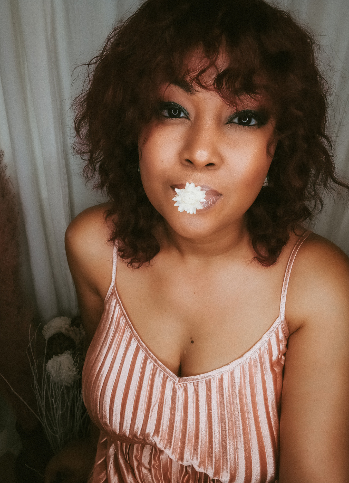 Bahamian blogger Rogan Smith poses in a satin dress with a flower in her mouth