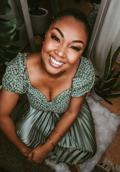 Black female blogger sits on ground and smiles at camera