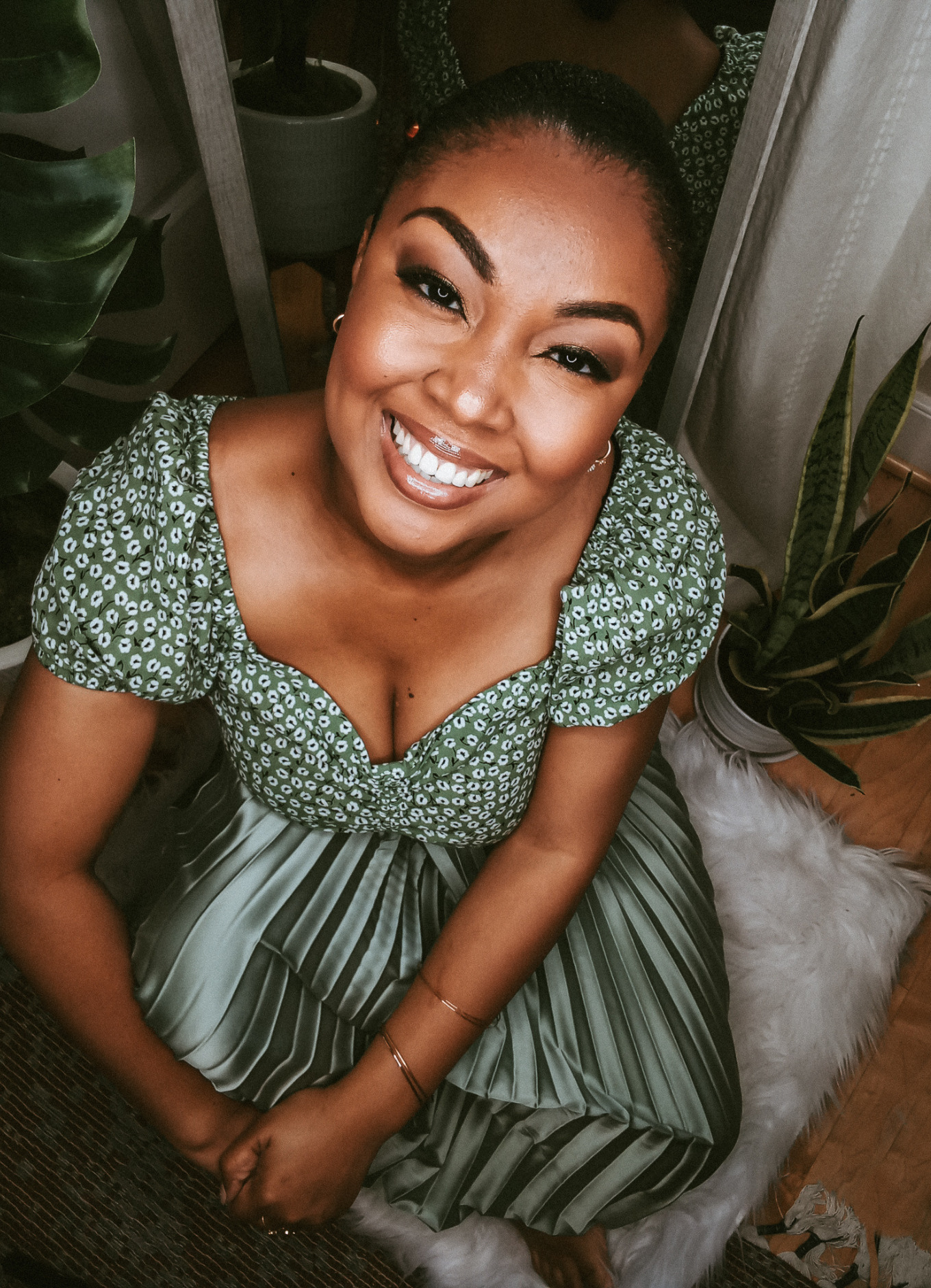 Black female blogger sits on ground and smiles at camera 