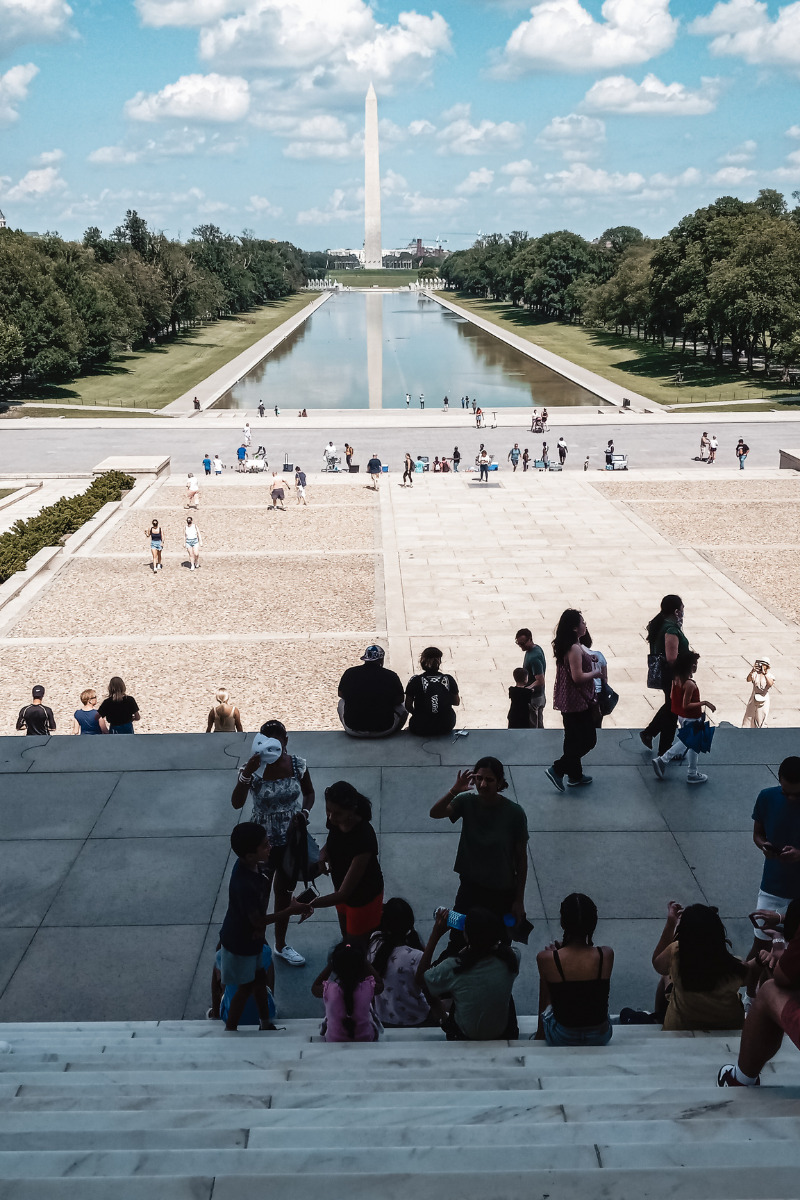 Photo of tourists sightseeing at the Lincoln Memorial. You can see the length of the National Mall