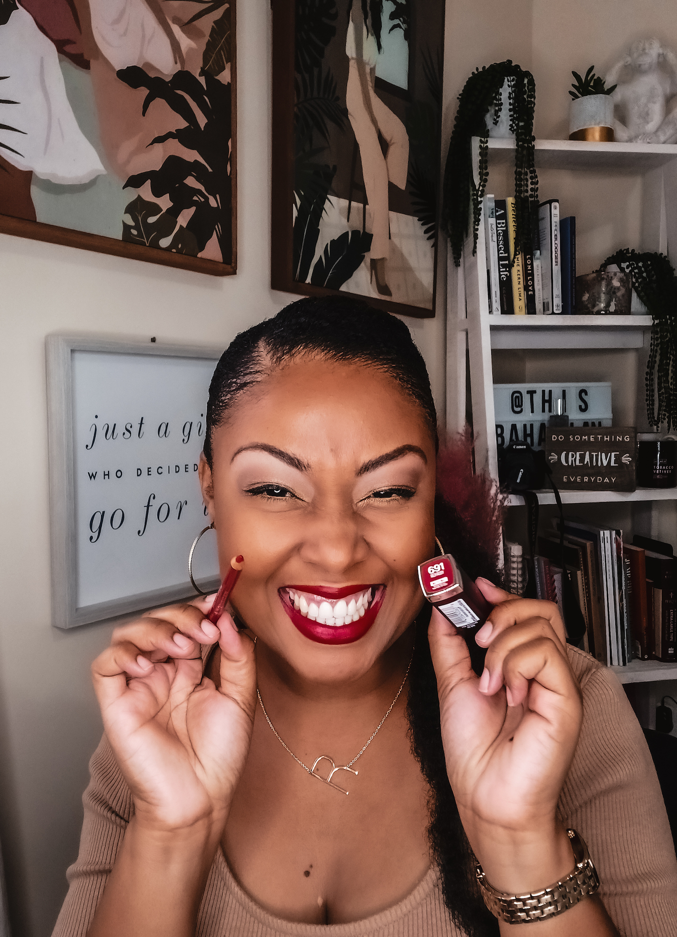 Light skinned black woman smiles while holding red lipstick