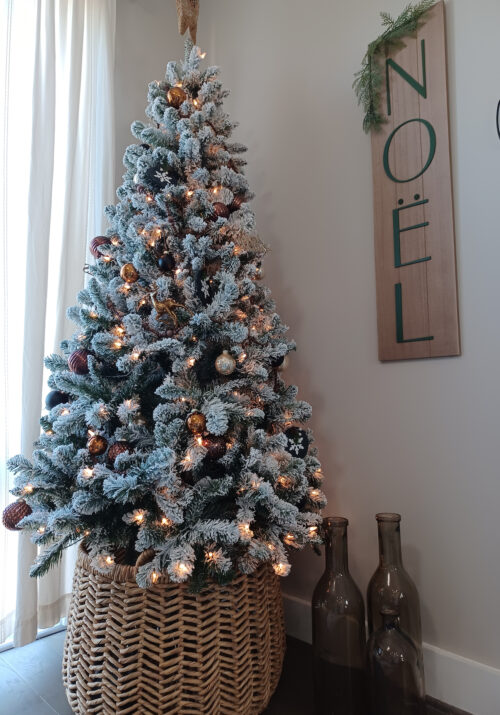 A six and a half foot flocked Christmas tree sits in the living room of a small apartment.