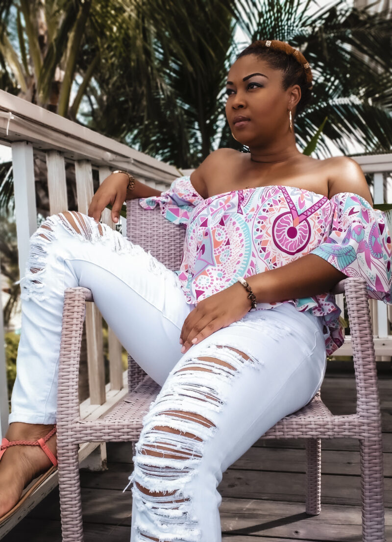the awful truth about visiting Nassau, Bahamas. This Bahamian Gyal blogger, Rogan sits on a chair on a balcony in Nassau, Bahamas.