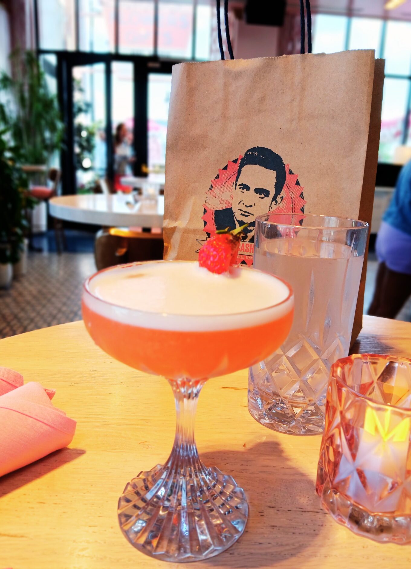 A pink cocktail in a rounded glass sits on a table in White Limozeen