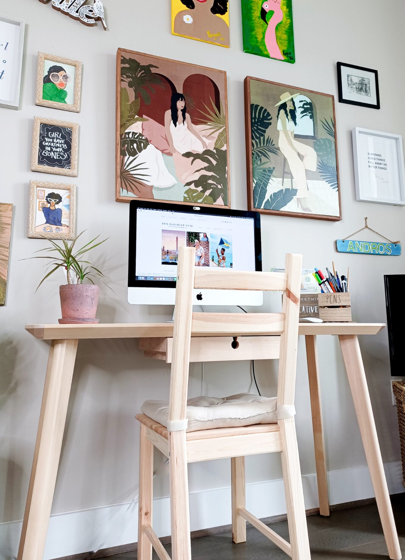 A tidy IKEA desk sits against a wall with a MAC computer sitting on top. A gallery wall can be seen in the background. It is the perfect work from home setup.