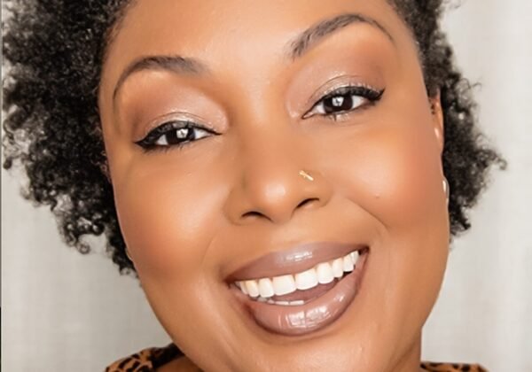 How to grow on YouTube. Here's a close up of This Bahamian Gyal blogger, Rogan smiling directly into the camera. She has a curly afro and is wearing a cheetah print blouse.