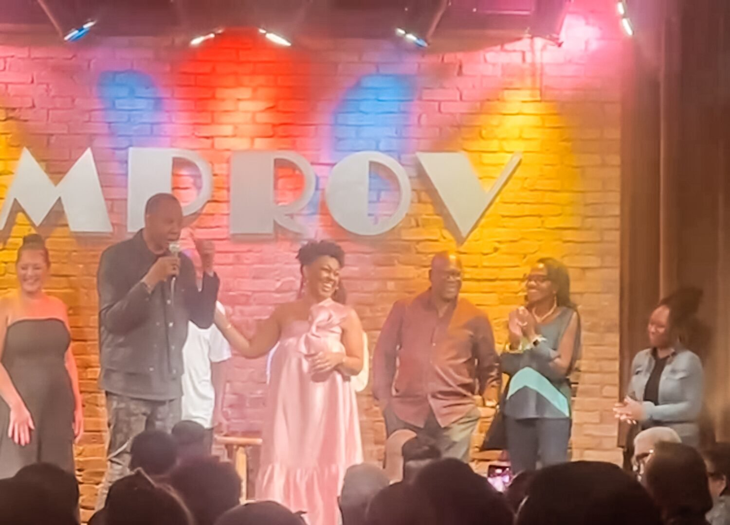 This Bahamian Gyal Blogger, Rogan shares a laugh on stage with comedian Mark Curry at Dallas Improv on August 29, 2025