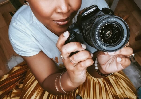 YouTube Channel Business - This Bahamian Gyal blogger, Rogan holds up a Canon camera and stares into the camera