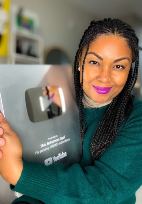 This Bahamian Gyal blogger, Rogan hugs her YouTube plaque for passing 100,000 subscribers. She now teaches how proper YouTube SEO helps channels grow.