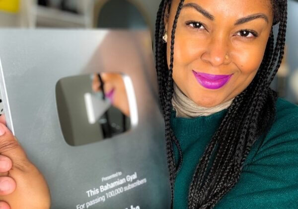 This Bahamian Gyal blogger, Rogan hugs her YouTube plaque for passing 100,000 subscribers. She now teaches how proper YouTube SEO helps channels grow.