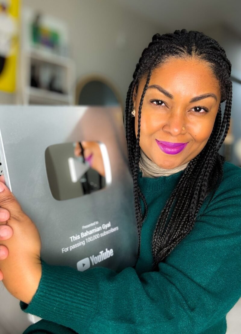 This Bahamian Gyal blogger, Rogan hugs her YouTube plaque for passing 100,000 subscribers. She now teaches how proper YouTube SEO helps channels grow.