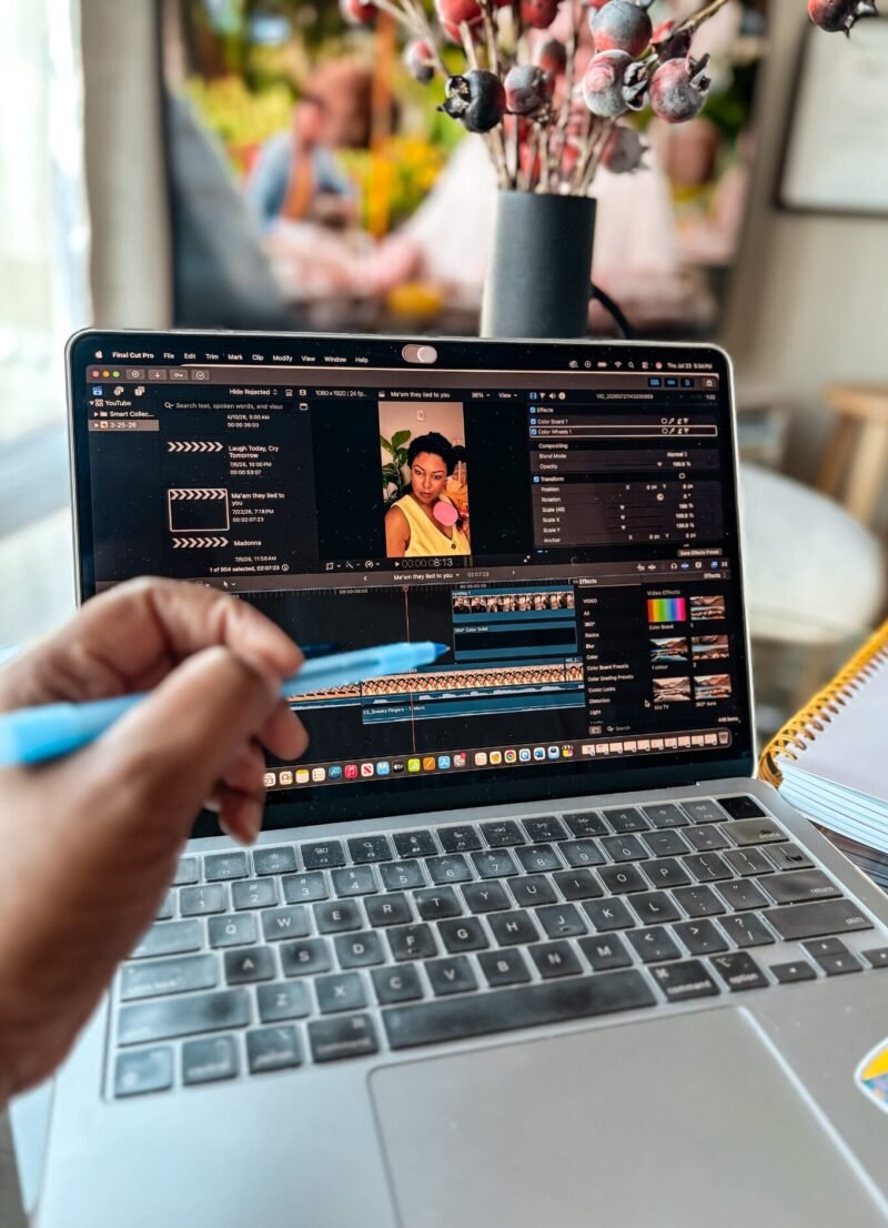 Creator workspace with a laptop displaying a YouTube Shorts editing timeline, alongside a notepad and flowers